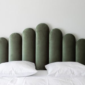 Hotelzimmer Bett mit grünem Samtende, Lampen und weißer Bettwäsche