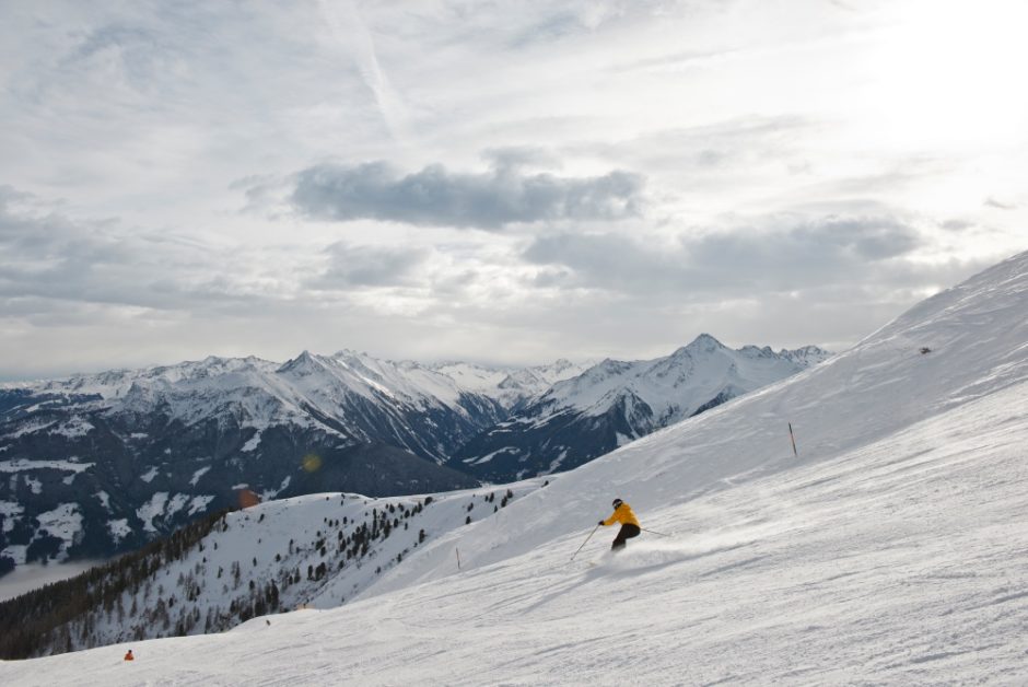 Person auf Ski auf der Piste mit Bergen im Hintergrund
