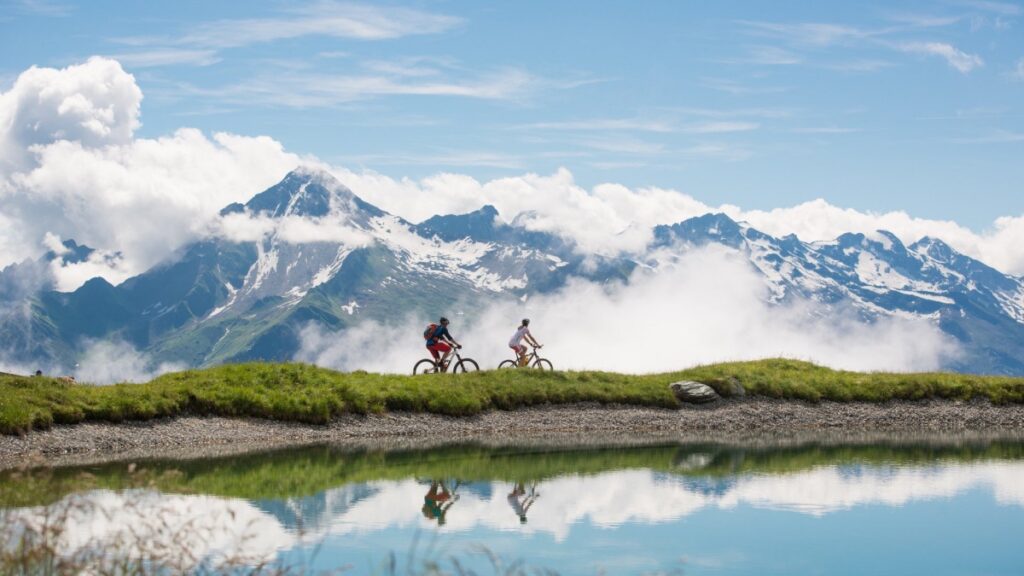 zwei radfahrer mit berge im hintergrund spiegeln sich im see