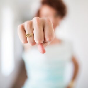 Powerfrau streckt ihre geballte Faust nach vorne und trägt einen Ring mit der Aufschrift I am bad ass.