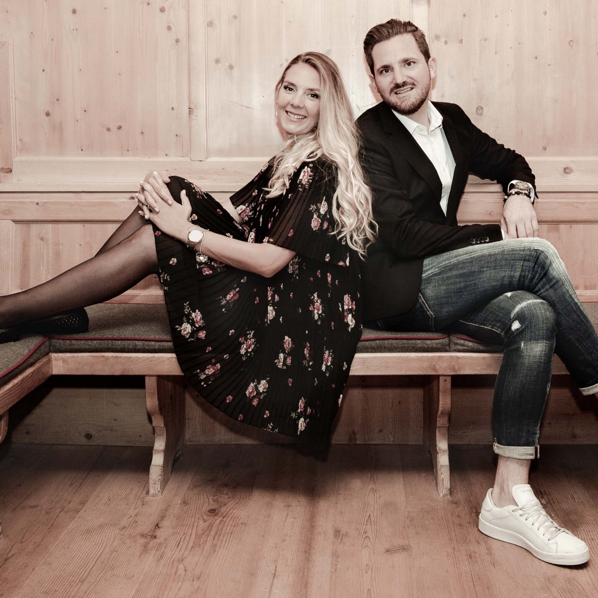 Traditionelle Gemütlichkeit Zwei Personen sitzen lächelnd auf einer Holzbank in traditionellem Ambiente.